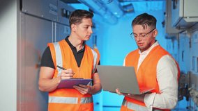 Two engineers collaborate in server room. Professionals discuss data on laptop, taking notes. Demonstrates teamwork, focus, diligence. - Powered by Shutterstock - Get 15% off with code: PIKWIZARD15