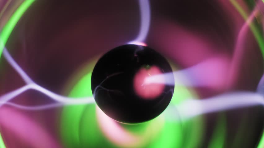 Macro view of a plasma ball central electrode emitting pink and purple electric bolts. Wavy ionized gas filaments and streamers with green light glow on a dark background. High voltage energy display.