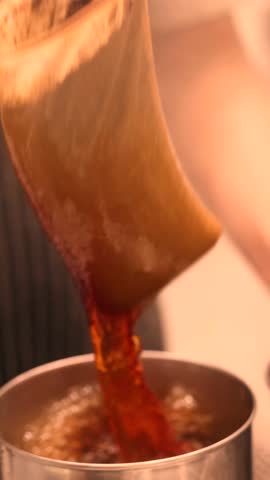 Action of pulling the chai in Singapore and Malaysia cafes where tea is poured from height mixing milk and sugar creating frothy layers inspired by traditional teh tarik coffee preparation