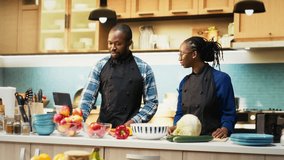 African american couple following online recipe for a fresh salad, looking at the steps and ensuring easy vegetables mix. Cute boyfriend and girlfriend cooking together for a vegan meal. Camera B. - Powered by Shutterstock - Get 15% off with code: PIKWIZARD15