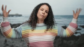 Woman enjoying peaceful moment at beach with colorful sweater and curly hair, against a serene ocean backdrop, conveying relaxation and freedom at the seaside. - Powered by Shutterstock - Get 15% off with code: PIKWIZARD15