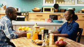 African american couple serving coffee in mugs and enjoying weekend morning together, bonding and relaxing at the breakfast table. Young happy people sharing a positive conversation. Camera B. - Powered by Shutterstock - Get 15% off with code: PIKWIZARD15