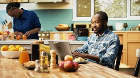 Joyous African American couple celebrating work win and good news, sharing breakfast while working remotely from home. Boyfriend and girlfriend feeling successful with the achievement. Camera B. - Powered by Shutterstock - Get 15% off with code: PIKWIZARD15