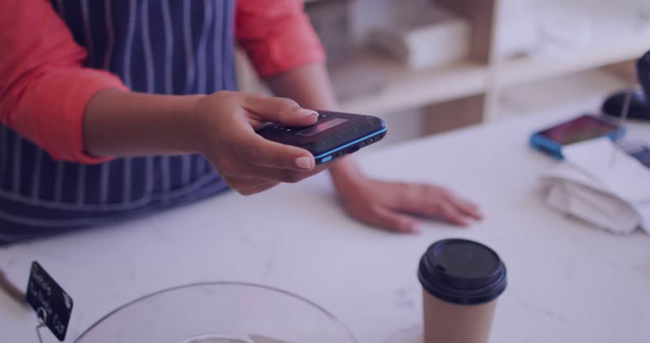 Cafe worker holding phone while cashier tapping card reader, HUD overlays animating during checkout. Contactless, payment, terminal, smartphone, coffee, cafe, transaction