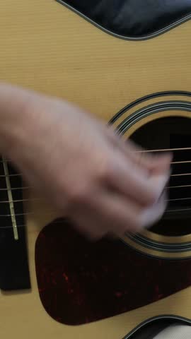 Vertical close-up of fast strumming on acoustic guitar, showcasing technique for trending online tutorials, music-learning platforms, and popular educational clips.