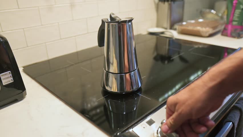 moka pot on induction stove during morning, contemporary breakfast setup with coffee brewing equipment present, stylish kitchen scene showing moka pot starting to heat for brewing coffee