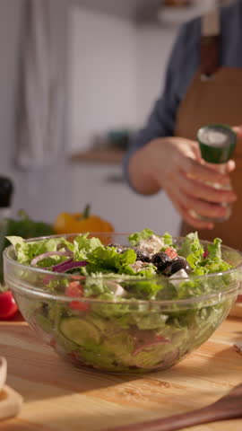 Organic food lifestyle female hand seasoning fresh green salad with spices slow motion vertical clip dietary nutrition concept clean eating plant based cooking