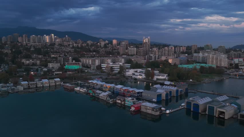 Aerial wide descending shot of floating homes and houseboats on the North Vancouver shore at twilight in British Columbia, Canada. 4K