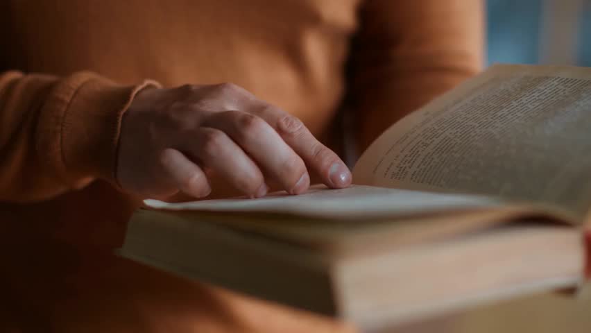 Close-up of an elderly man reading a book, following letters with his finger, highlighting aging eyesight, vision challenges, and lifelong learning.