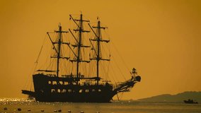 A dramatic silhouette of a pirate ship sails across the sea at sunset, with golden skies and calm waters, evoking adventure, mystery, and cinematic maritime atmosphere. - Powered by Shutterstock - Get 15% off with code: PIKWIZARD15