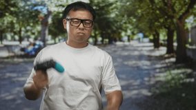 Man holds game controller with both hands and squints eyes while pressing buttons in forest setting; concentration. - Powered by Shutterstock - Get 15% off with code: PIKWIZARD15