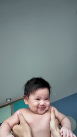 A mother playing with her baby on the bed, fostering bonding and stimulating early development in a warm, cozy atmosphere