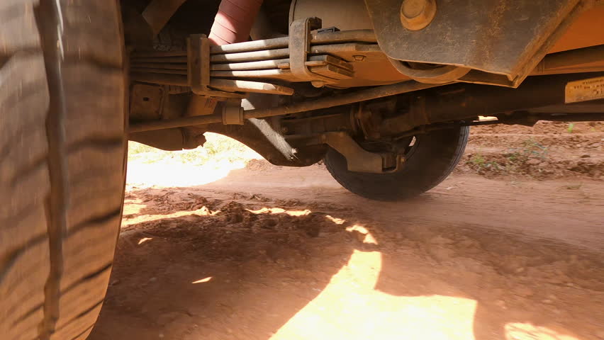 ow angle close up of a car tire driving on a dusty gravel road in rural countryside, capturing texture, motion and rugged travel atmosphere for road trip and transportation concepts