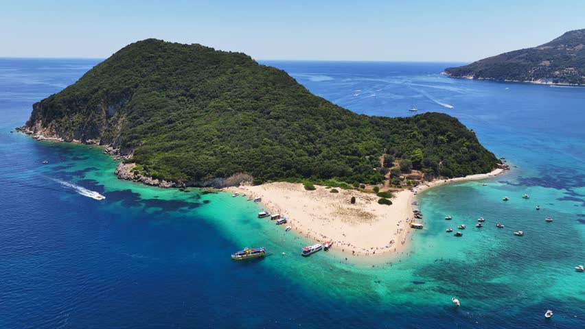 Aerial drone cinematic video of scenic caves and turquoise beach in paradise island of Marathonisi in bay of Laganas, visited by small boats a true tourist attraction, Zakithnos island, Ionian, Greece