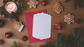 Christmas greeting card with gingerbread cookies, red envelope, candle and pine branches on wooden table - Powered by Shutterstock - Get 15% off with code: PIKWIZARD15