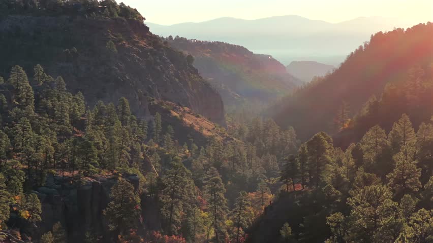 Cinematic drone shot rising over a dramatic canyon landscape at golden hour, with soft light leaks and deep shadows creating a dynamic parallax effect. Ideal for travel, nature, and scenic B-roll.