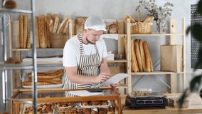 Man owner is busy checking paper documents, calculating income and expenses, expected increase in profit. Checks bill of lading. Bakery employee in apron examines documents, ponders debt restructuring - Powered by Shutterstock - Get 15% off with code: PIKWIZARD15