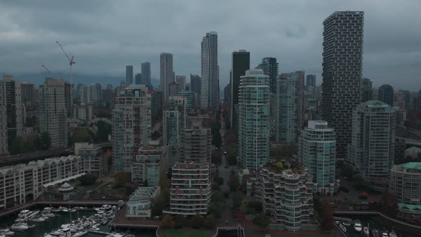 Wide rising aerial shot of the downtown skyline on a rainy afternoon in Vancouver, British Columbia, Canada. 4K