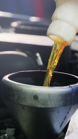 Mechanic replaces special fuel and engine oil in vehicle. Mechanic works on repair of automobile pouring substance into round container