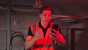Worker wearing safety vest displays concern and confusion while viewing urgent red warning on smartphone screen. Communication and problem-solving actions indicated during system alert. - Powered by Shutterstock - Get 15% off with code: PIKWIZARD15