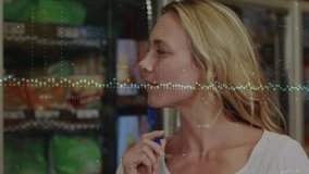 Woman turning to fridge shelves in grocery writing on pad and checking prices with dotted overlay. Shopper, notepad, pen, analytics, data, refrigeration, display - Powered by Shutterstock - Get 15% off with code: PIKWIZARD15