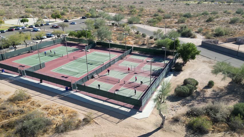 An exhilarating aerial view capturing tennis players in action at Prospector Park in Apache Junction, Arizona. Surrounded by the desert landscape
