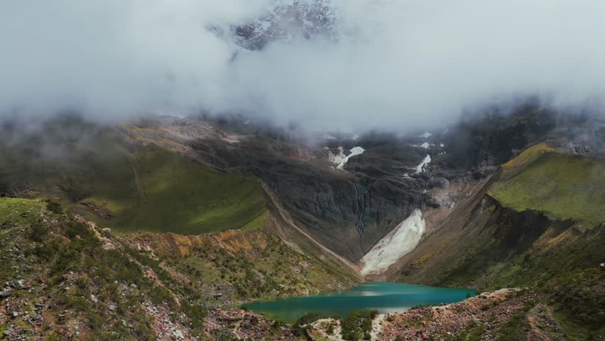 Laguna Lake Humantay snow capped high altitude glacier Humantay Salkantay mountain trek Peru aerial drone rainy season sunny fog clouds hiking Cusco Peruvian Andes range morning circle right pan up