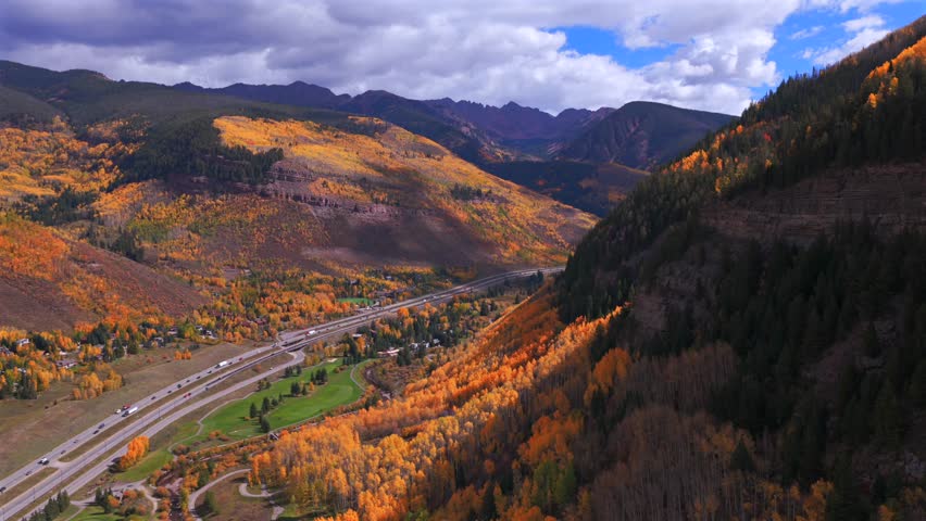 Vail Golf Club Vail Colorado Gore RangeRocky Mountains aerial drone fall autumn Vail Pass cars traffic i70 highway colorful aspen trees morning blue skies sunny clouds circle left motion