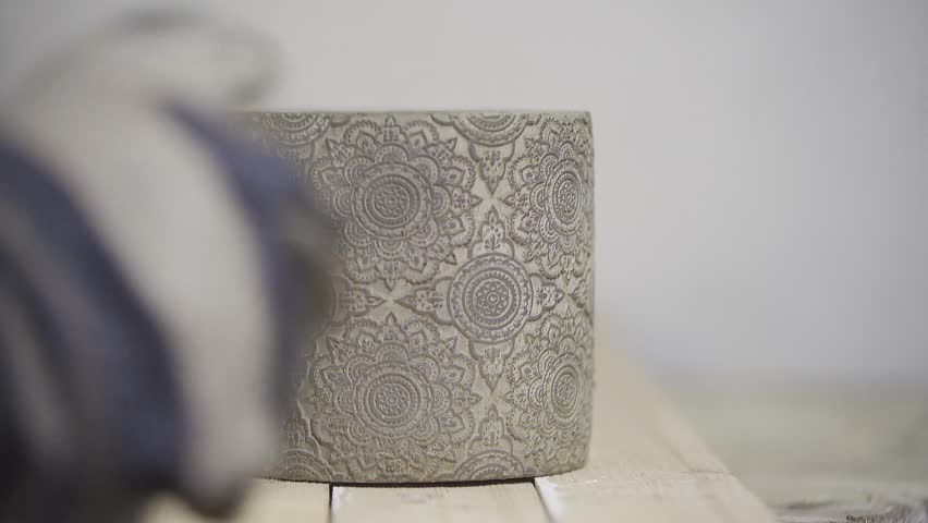 A close-up shot of a person spray painting a flower pot with black paint. The even mist from the spray can covers the surface smoothly, highlighting DIY customization, creative home decor and precise 