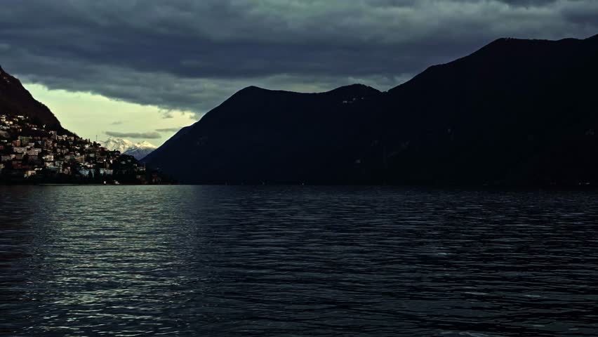 Lugano, Ticino, Switzerland – January 2, 2024: Overcast winter view across Lake Lugano facing Monte Brè and the distant Italian Alps.