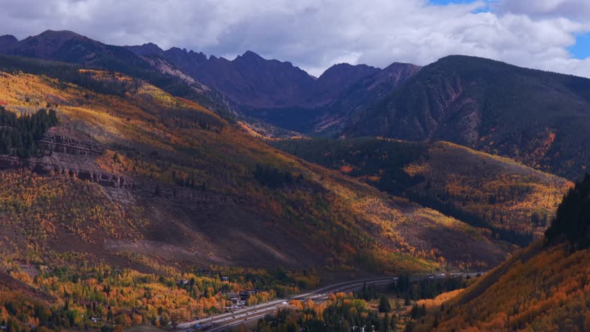 Vail Pass cars traffic i70 interstate highway Vail Colorado Rocky Mountains Gore Range drone aerial fall autumn season colorful quaking aspen trees morning blue skies clouds parallax circle right