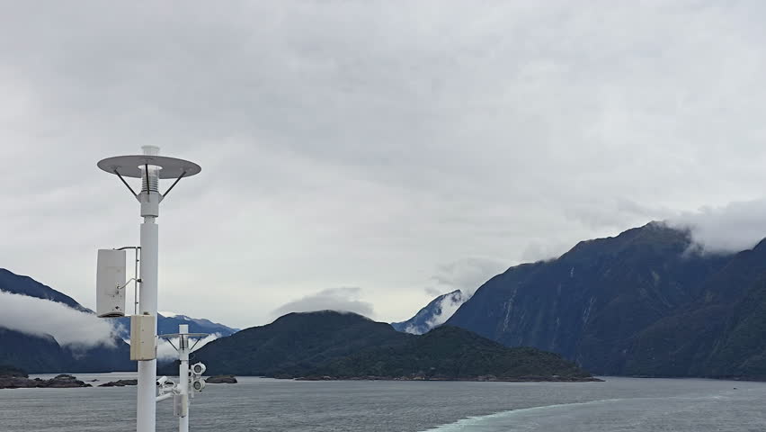 Milford Sound, Fiordland National Park, New Zealand dramatic fjord landscape with steep forested peaks, mist clad summits and calm reflective waters under moody clouds