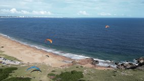 An aerial view of Punta Ballena shoreline in Punta del Este, Uruguay, with paragliders soaring above the coast as waves brushing the sandy beach below - Powered by Shutterstock - Get 15% off with code: PIKWIZARD15