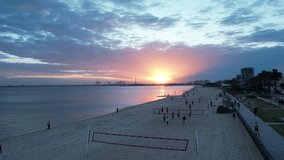 A Stunning aerial captures beach volleyball courts in Melbourne glowing under golden hour light, with players in motion and long shadows on the sand - Powered by Shutterstock - Get 15% off with code: PIKWIZARD15
