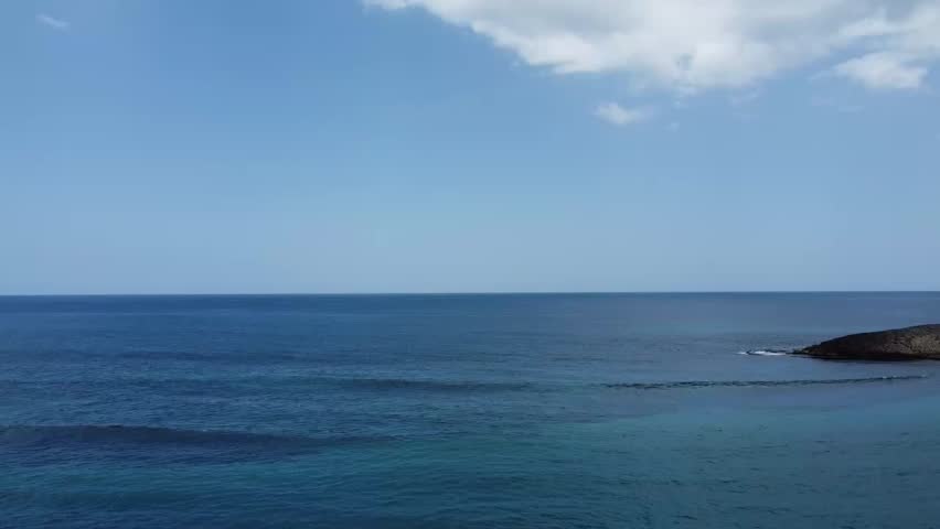 A drone footage of a paraglider paragliding over the Montones Beach during daytime in Isabela, Puerto Rico