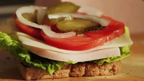 Close up of a homemade sandwich, toasted bread with ham juicy tomato, pickled cucumber, onion and lettuce. High quality 4k footage - Powered by Shutterstock - Get 15% off with code: PIKWIZARD15