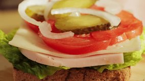 Close up of a homemade sandwich, toasted bread with ham juicy tomato, pickled cucumber, onion and lettuce. High quality 4k footage - Powered by Shutterstock - Get 15% off with code: PIKWIZARD15