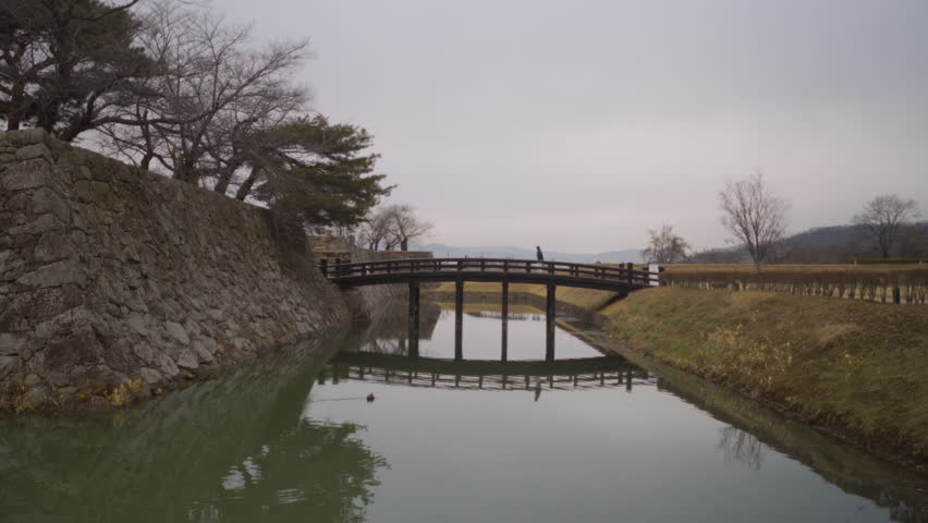 Man walks on a wooden bridge over a molt, Kawanakajima Battleground, Japan