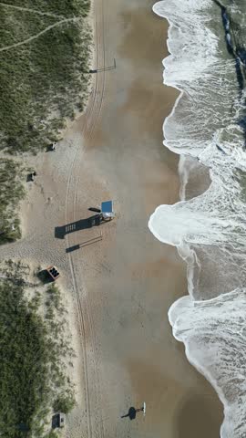A drone footage above surfer with board walking to lIfeguard station along the coast