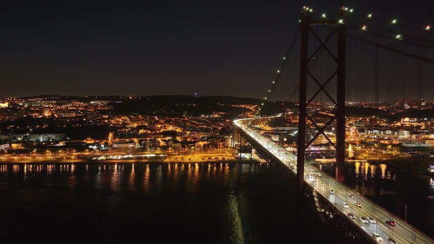 Aerial drone shot towards the 25th April Bridge, Ponte 25 de Abril, and city skyline in Lisbon, Portugal, Europe. Night shot in ProRes 422 HQ