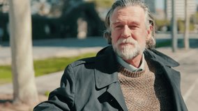 Portrait of a thoughtful senior man sitting on a park bench. He smiles and looks around. Mature businessman taking a break in the city. - Powered by Shutterstock - Get 15% off with code: PIKWIZARD15