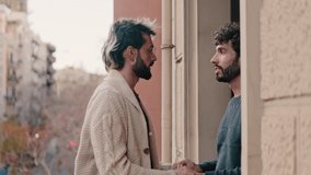 Affectionate gay couple holding hands, talking and sharing a moment together at home on their apartment balcony. - Powered by Shutterstock - Get 15% off with code: PIKWIZARD15