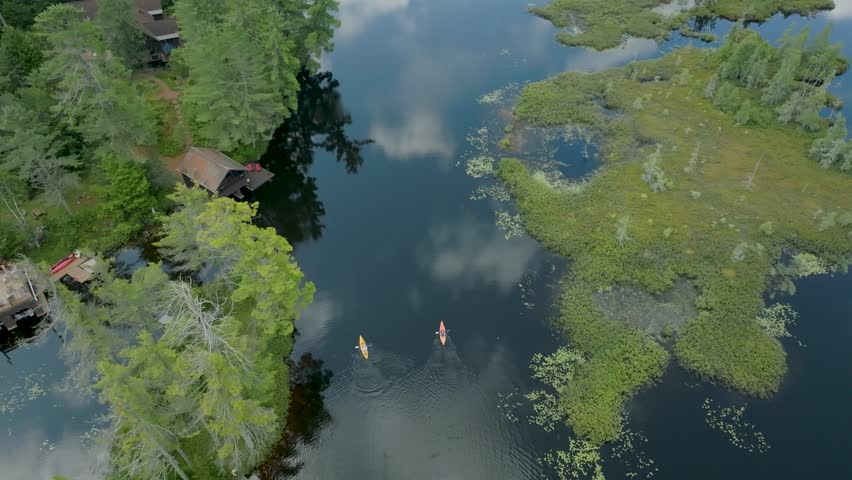 Drone overhead view of 2 kayakers paddling on a summer day on Rainbow Lake in the Adirondack Mountains in New York