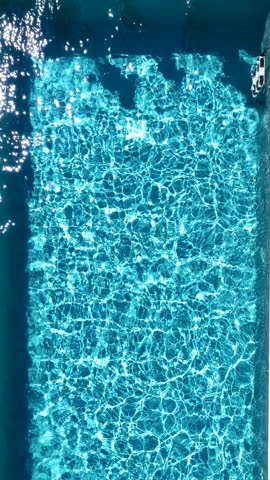 Aerial overhead view of a happy family jumping together in the pool as a summer travel concept with copy space