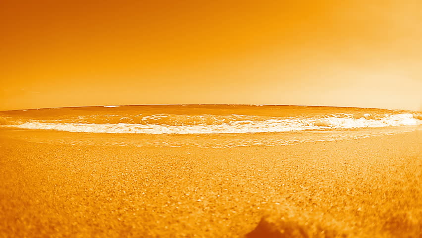 The bright blue sky. Sandy beach. Surf. Point of shooting at the level of sand.