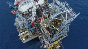 High-tech oil rig floats on deep blue waters, bustling with activity. Workers maneuver machinery while cranes lift heavy equipment, demonstrating energy industry operations. - Powered by Shutterstock - Get 15% off with code: PIKWIZARD15