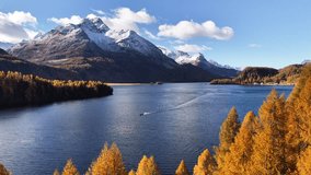 Peaceful autumn view of Lake Sils (Silsersee) in Switzerland’s Engadin valley. A small boat is floating on the calm blue waters where golden larch forests meet the alpine edge. - Powered by Shutterstock - Get 15% off with code: PIKWIZARD15