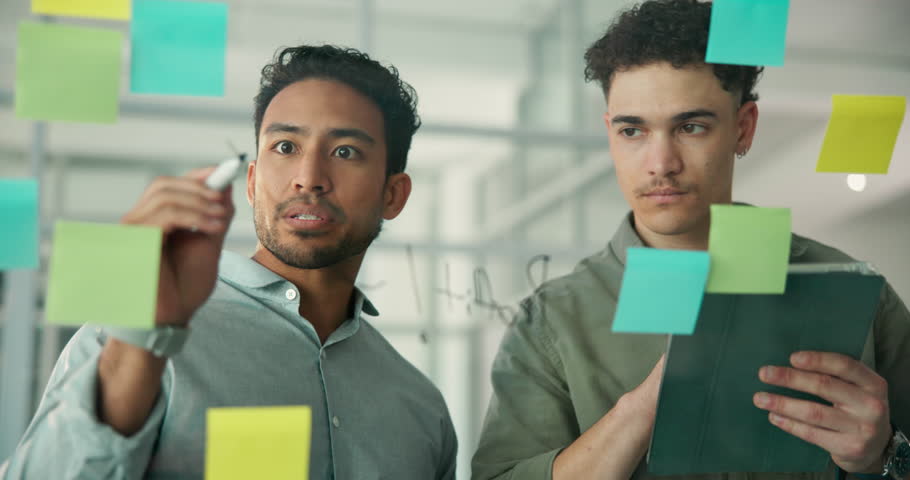 Businessmen, schedule planning and brainstorming with tablet for tasks or project agenda in office. Male people, team or colleagues with technology, sticky note or priority for ideas on glass board