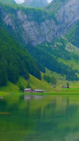 Beautiful mountain landscape with calm lake reflecting nature and small cabins in serene setting
