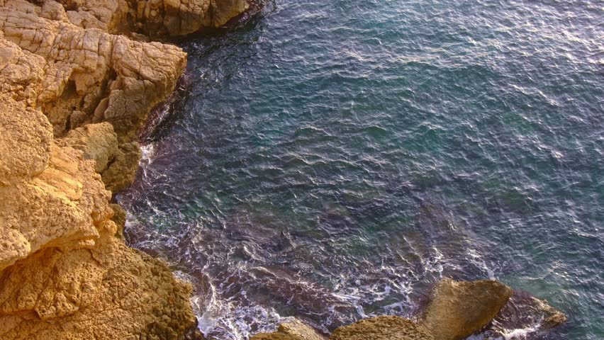 Cala Tio Ximo coastline captured in December evening light. Tranquil winter sea, soft sunset glow, peaceful view of small island near Benidorm. Quiet natural beauty, no people, only sea and sky.